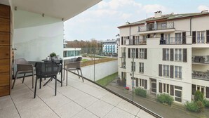 Un balcón con mobiliario exterior, vistas a edificios vecinos y un cielo despejado.