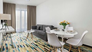Una habitación de hotel moderna con comedor, sofá y alfombra estampada.
