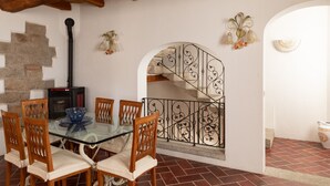 A dining area with a glass table, wooden chairs, a stone wall, a fireplace, and a decorative metal staircase. - Casa al Duomo by Wonderful Italy (Telti)