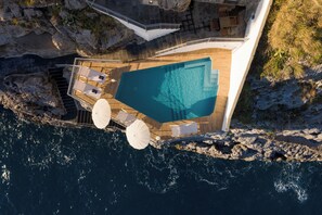 Ein Luftbild einer luxuriösen Yacht mit großem Pool, Holzdeck und Sitzbereich im Freien.