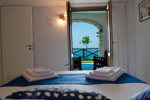 Ein Hotelzimmer mit Bett, Meerblick und einem Balkon mit Stühlen.