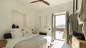 Ein Schlafzimmer mit Bett, Deckenventilator, Kommode und Blick ins Freie.