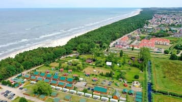 An aerial view of a coastal area with a beach, a row of mobile homes, and a residential area with houses.