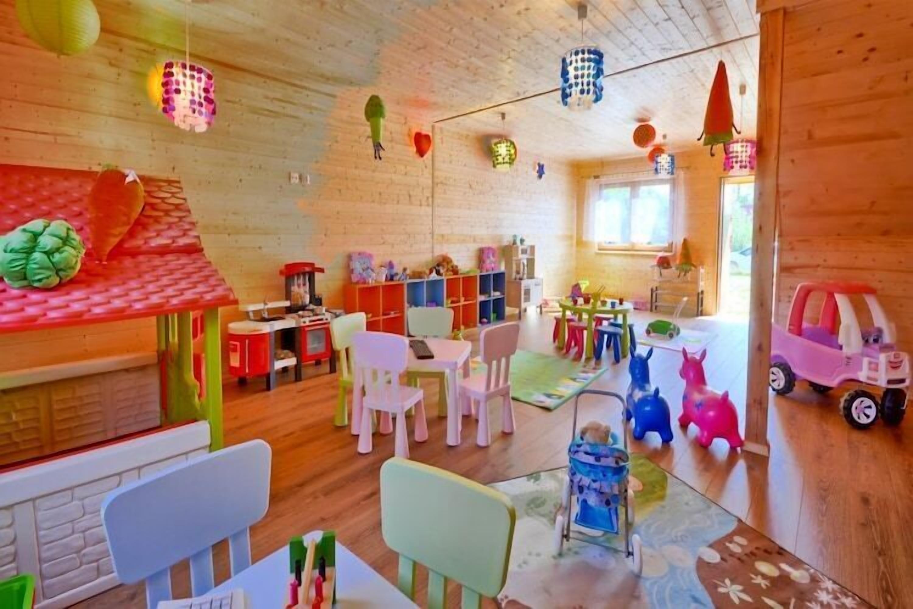 A brightly lit room with wooden walls, colorful chairs, and a variety of toys and decorations.