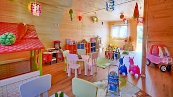 A brightly lit room with wooden walls, colorful chairs, and a variety of toys and decorations.