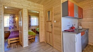 A compact wooden cabin with a small kitchenette, a single bed, and a bathroom. - Elegant House with Terrace Near Sea (Karwia)