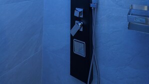 A modern shower with a control panel and a handheld showerhead. - Cozy studio apartment within walking distance of hospital (Vercelli)