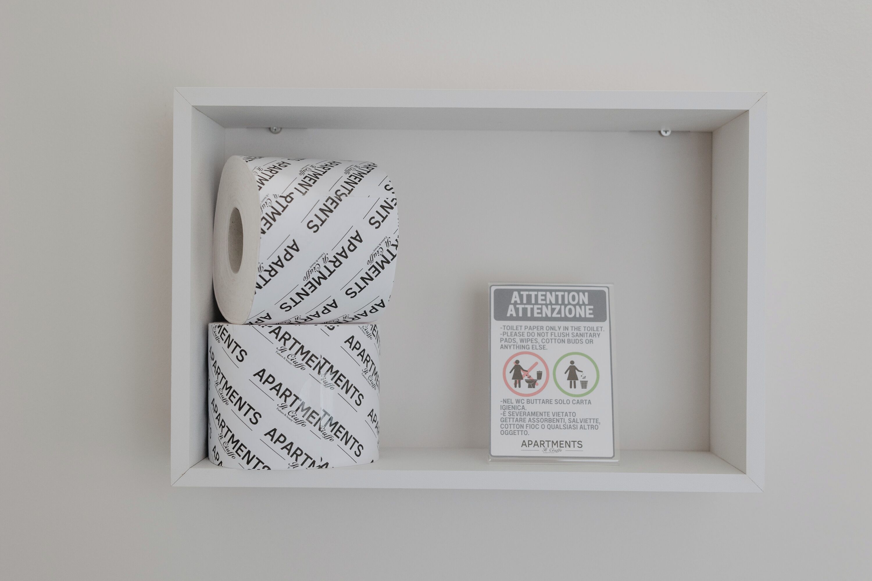 Ein weißer Karton mit Toilettenpapier und einem Schild mit Anweisungen auf Italienisch.