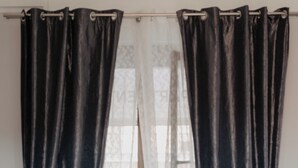 A room with a window, black curtains tied at the bottom, and a wooden floor. - Cozy studio apartment within walking distance of hospital (Vercelli)