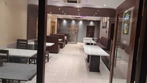 Un restaurante con cabinas y mesas, piso de baldosas y una pared decorada con obras de arte.