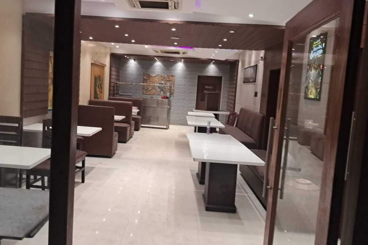 Un restaurante con cabinas y mesas, piso de baldosas y una pared decorada con obras de arte.