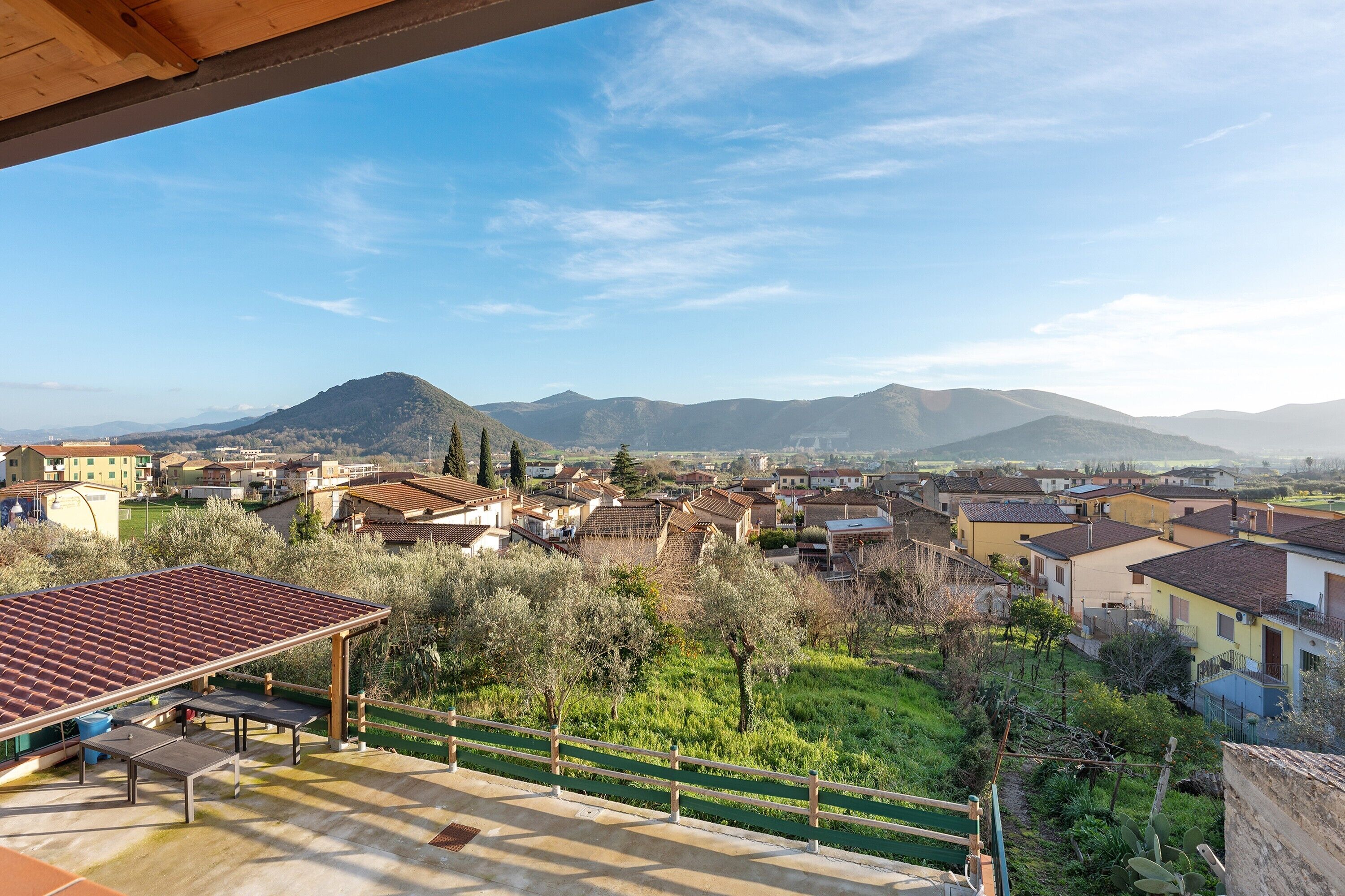 A residential area with houses, a mountain in the background, and a covered outdoor seating area.