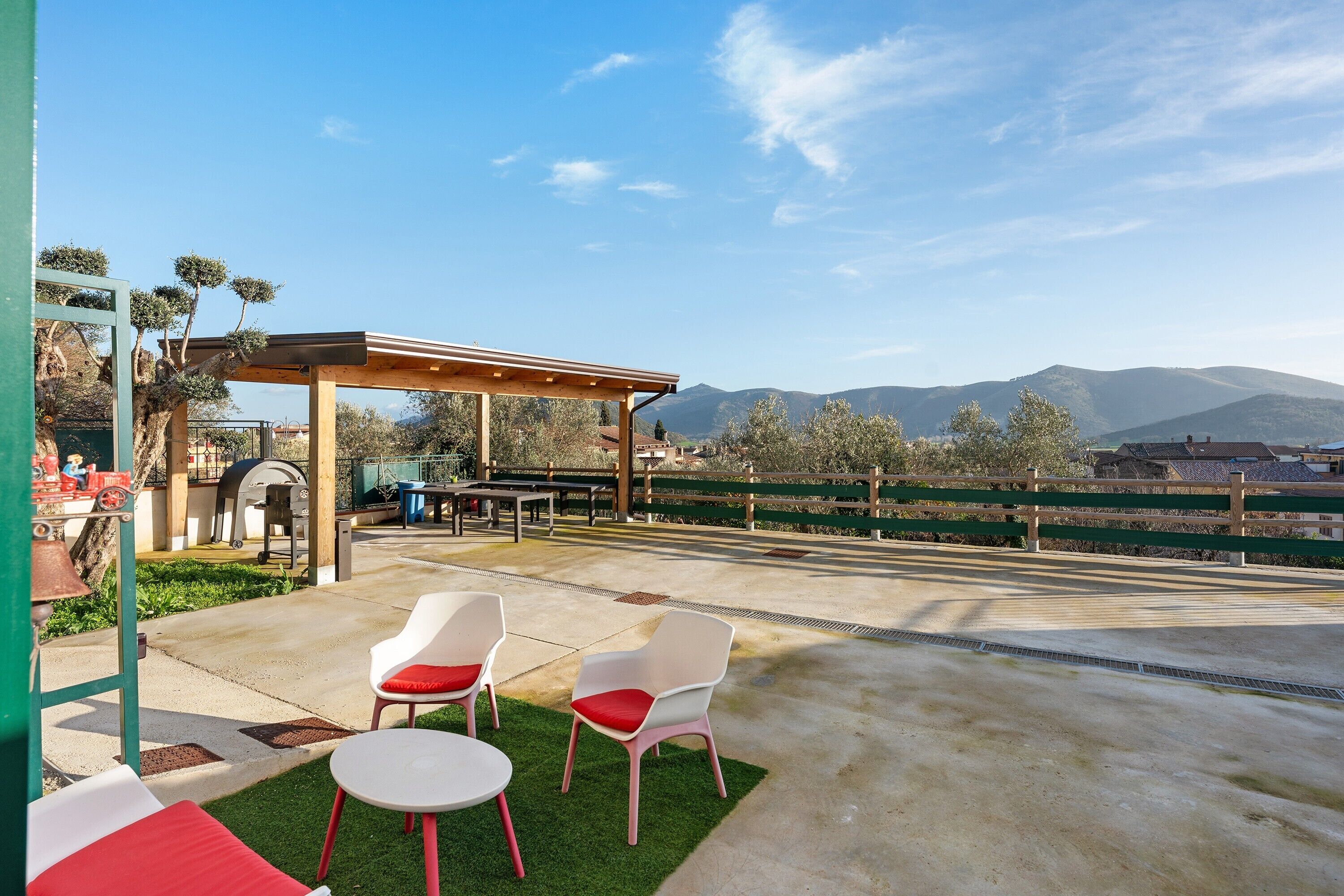 An outdoor patio with chairs and a pergola, a barbecue grill, and a view of mountains.