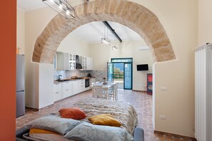 A bedroom with a bed, a kitchen with white cabinets, and a dining area with a table and chairs. - Holiday Home 'La Casa di Paddington' with Private Pool, Wi-Fi & Air Conditioning (Piana di Monte Verna)