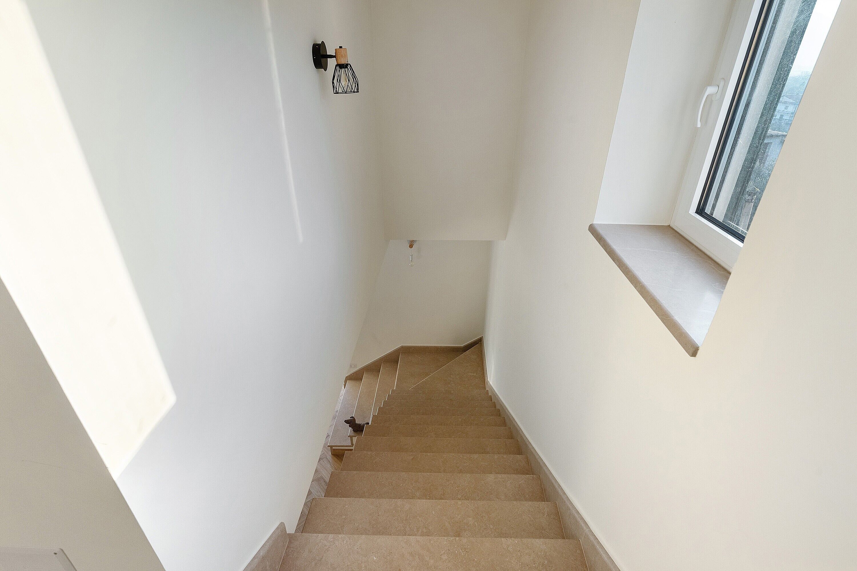 A staircase with a handrail, a small shelf, and a window with a view.