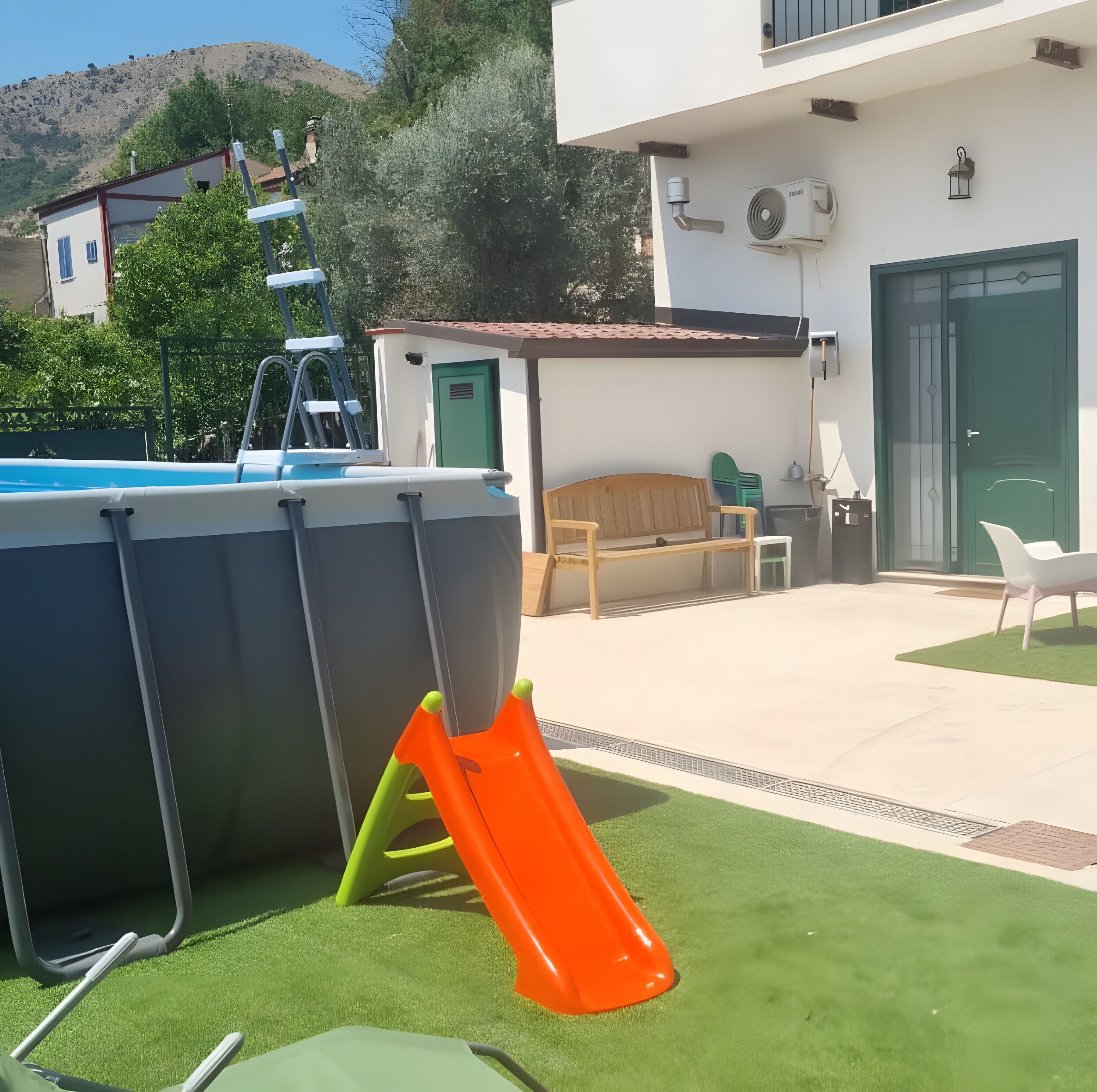 A swimming pool with a slide, a wooden bench, and a green door.
