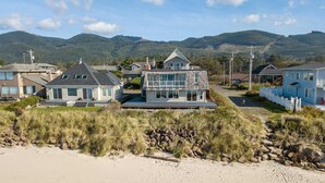 Ein Küstenwohngebiet mit Häusern, einem Sandstrand und Bergen im Hintergrund.