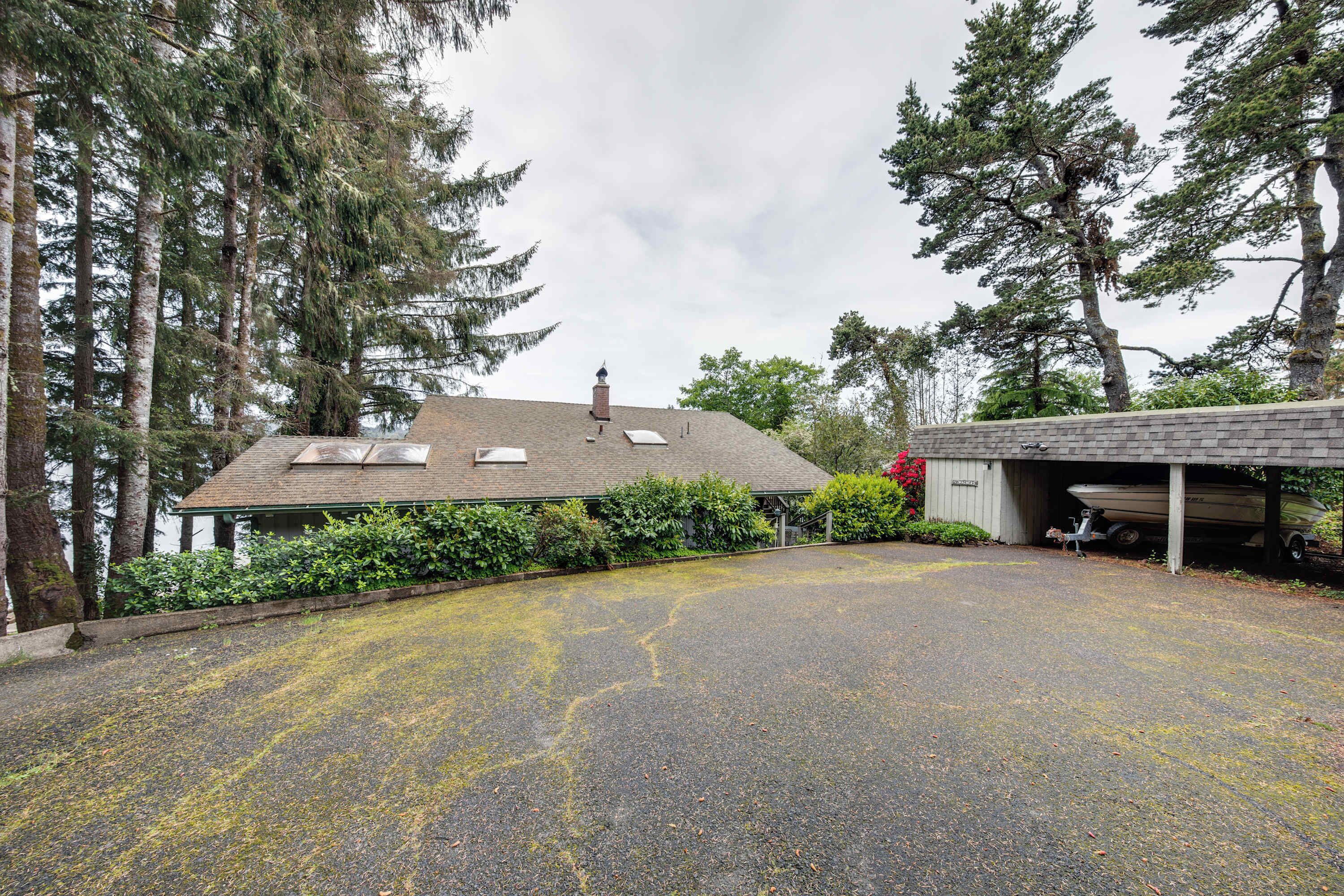 A house with a covered garage, a driveway, and a boat docked inside.