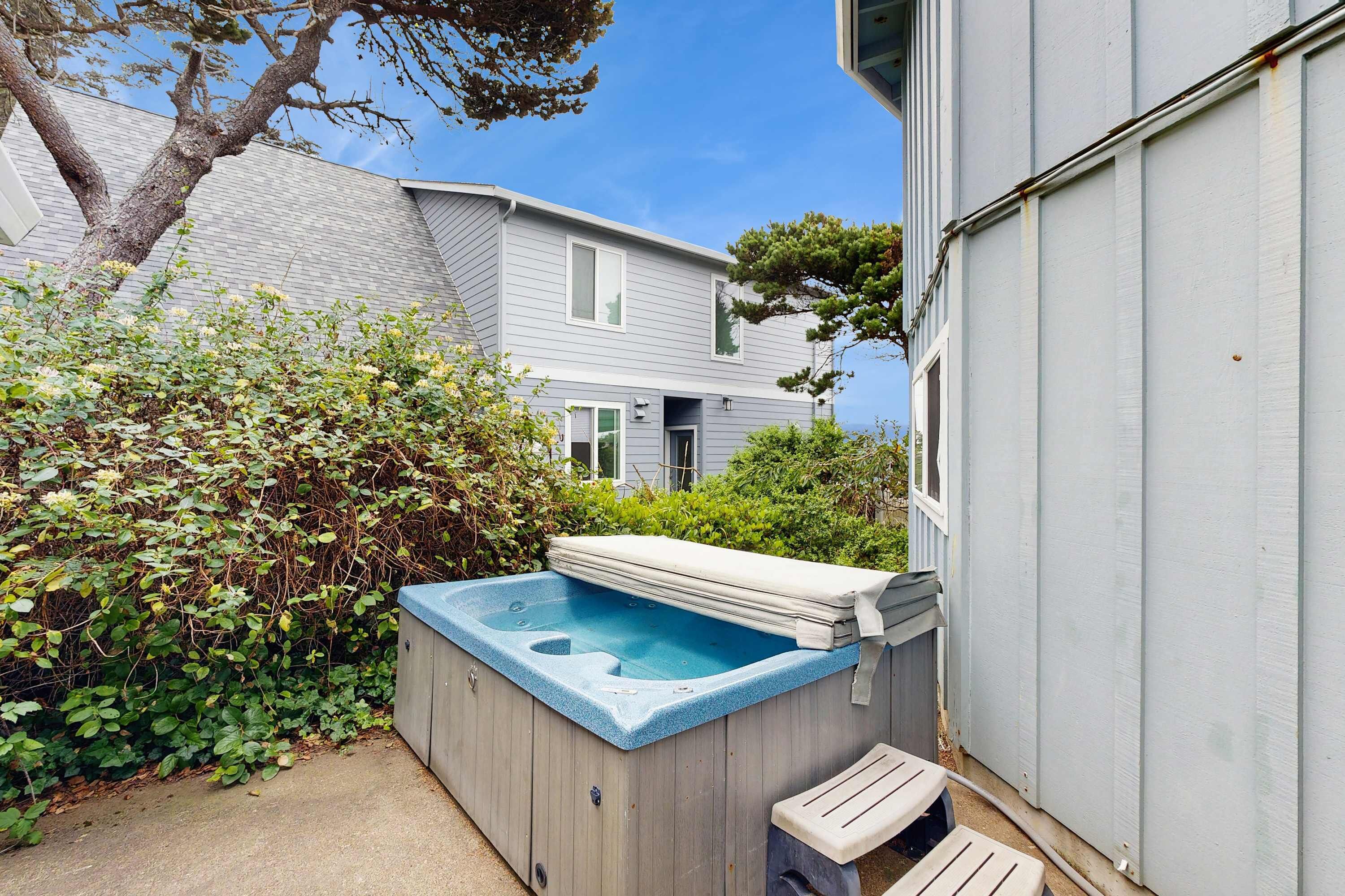 Un jardin avec un jacuzzi, une terrasse en bois et une maison en arrière-plan.