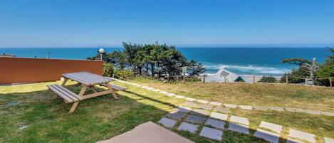 A patio with a picnic table overlooking the ocean.