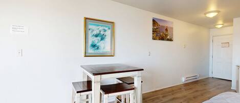 A room with a white table and two chairs, a painting on the wall, and a door.