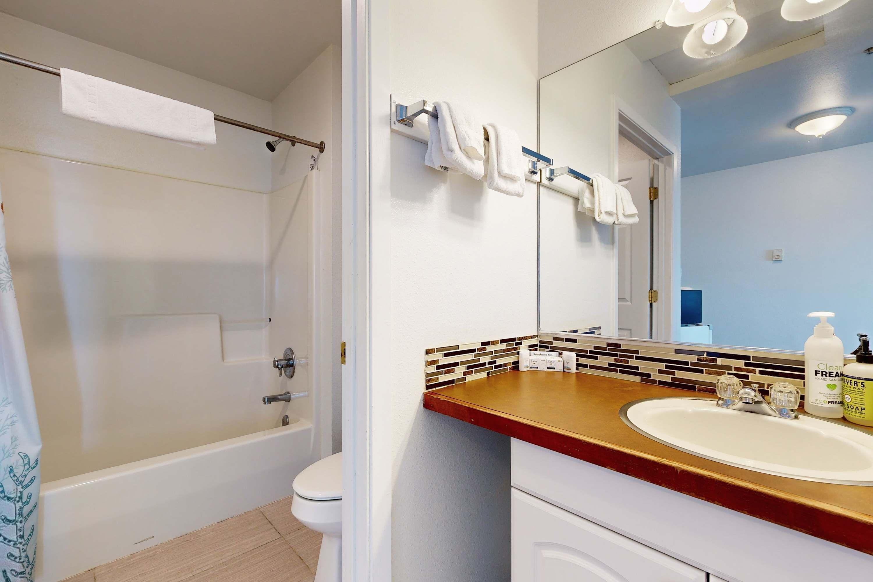 A bathroom with a bathtub, toilet, and a sink with a mirror above it.