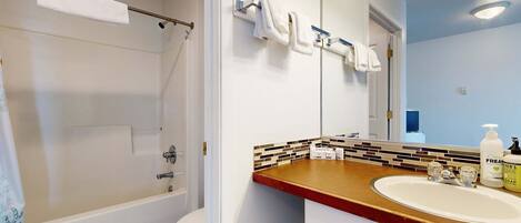 A bathroom with a bathtub, toilet, and a sink with a mirror above it.
