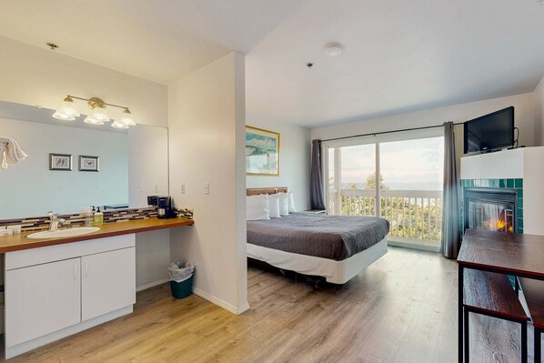 Une chambre avec un lit, une télévision, une cheminée et un balcon offrant une vue.