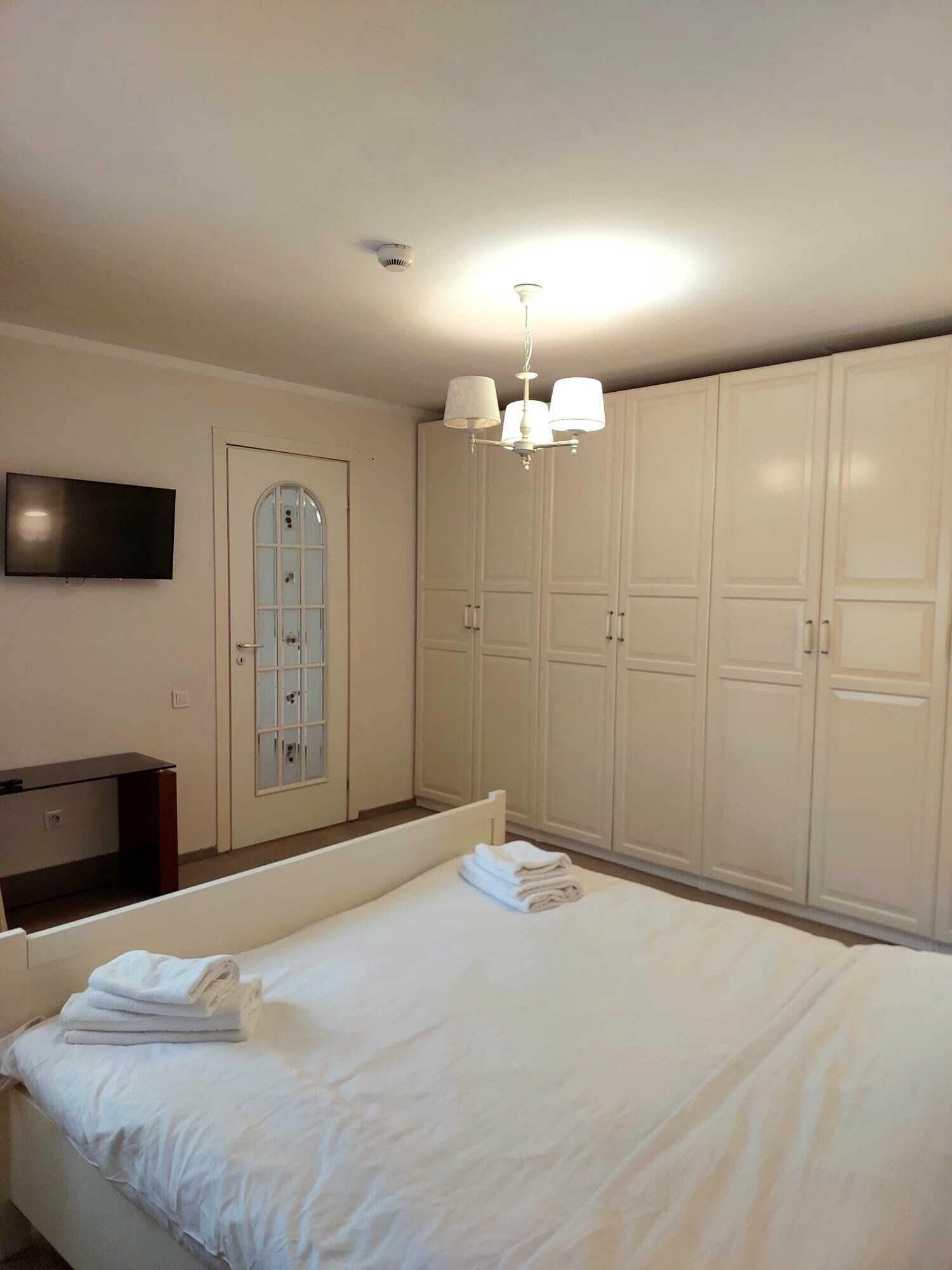 Un dormitorio con cama, televisor, armario y candelabro.