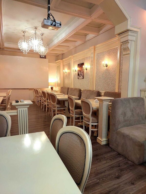 Un espace repas avec des tables et des chaises en bois, un lustre et des appliques murales.
