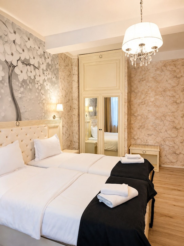 A hotel room with a large bed, a mirror, a chandelier, and a wall with a floral design. - Carol Boutique (Bucharest)