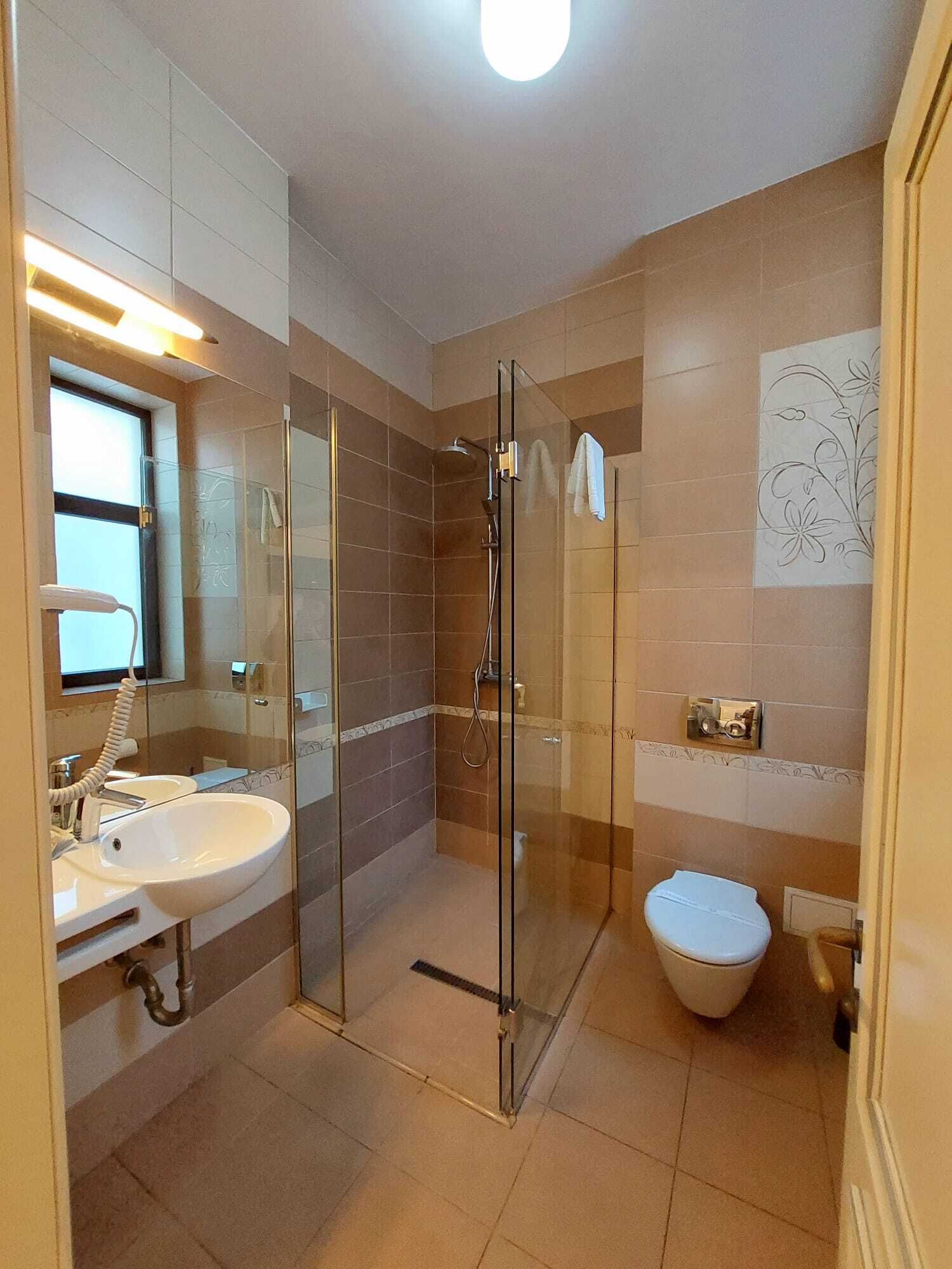 A modern bathroom with a glass-enclosed shower, a white sink, and a toilet.
