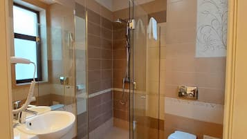 A modern bathroom with a glass-enclosed shower, a white sink, and a toilet.