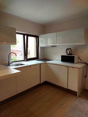 A kitchen with a window, a sink, cabinets, and a microwave. - Carol Boutique (Bucharest)