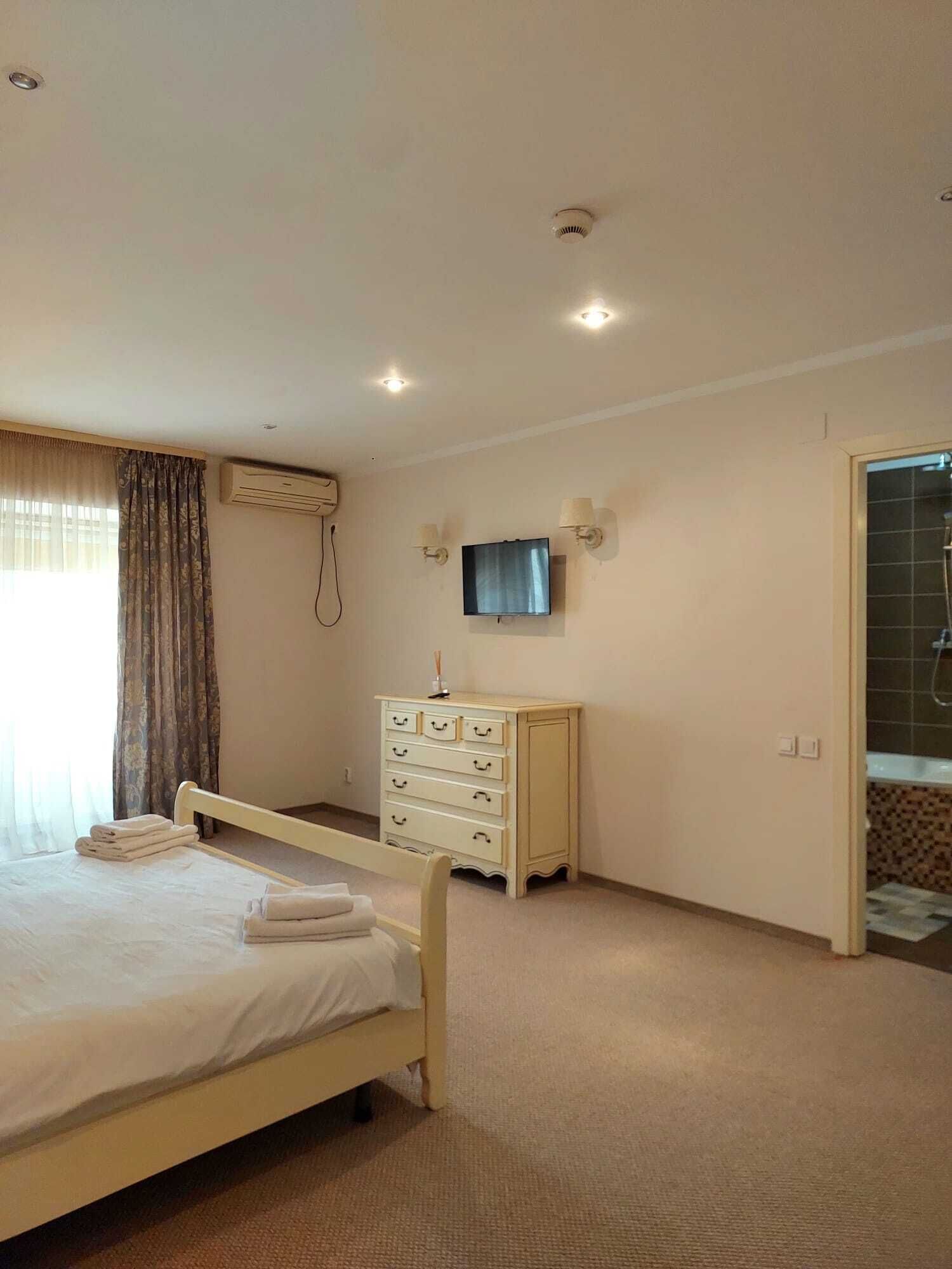 Un dormitorio con cama, cómoda, televisor y zona de ducha.