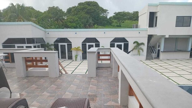 Una terraza en la azotea con mobiliario exterior, piscina y vistas a un edificio moderno con numerosas ventanas.