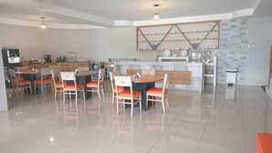 Una cocina amplia con electrodomésticos modernos, un comedor con sillas y suelo de baldosas.