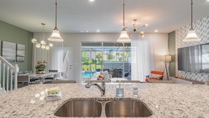 A modern kitchen with granite countertops, stainless steel sink, and pendant lighting. - Disney 5BR Villa w/ Pool Solterra Resort (Davenport)