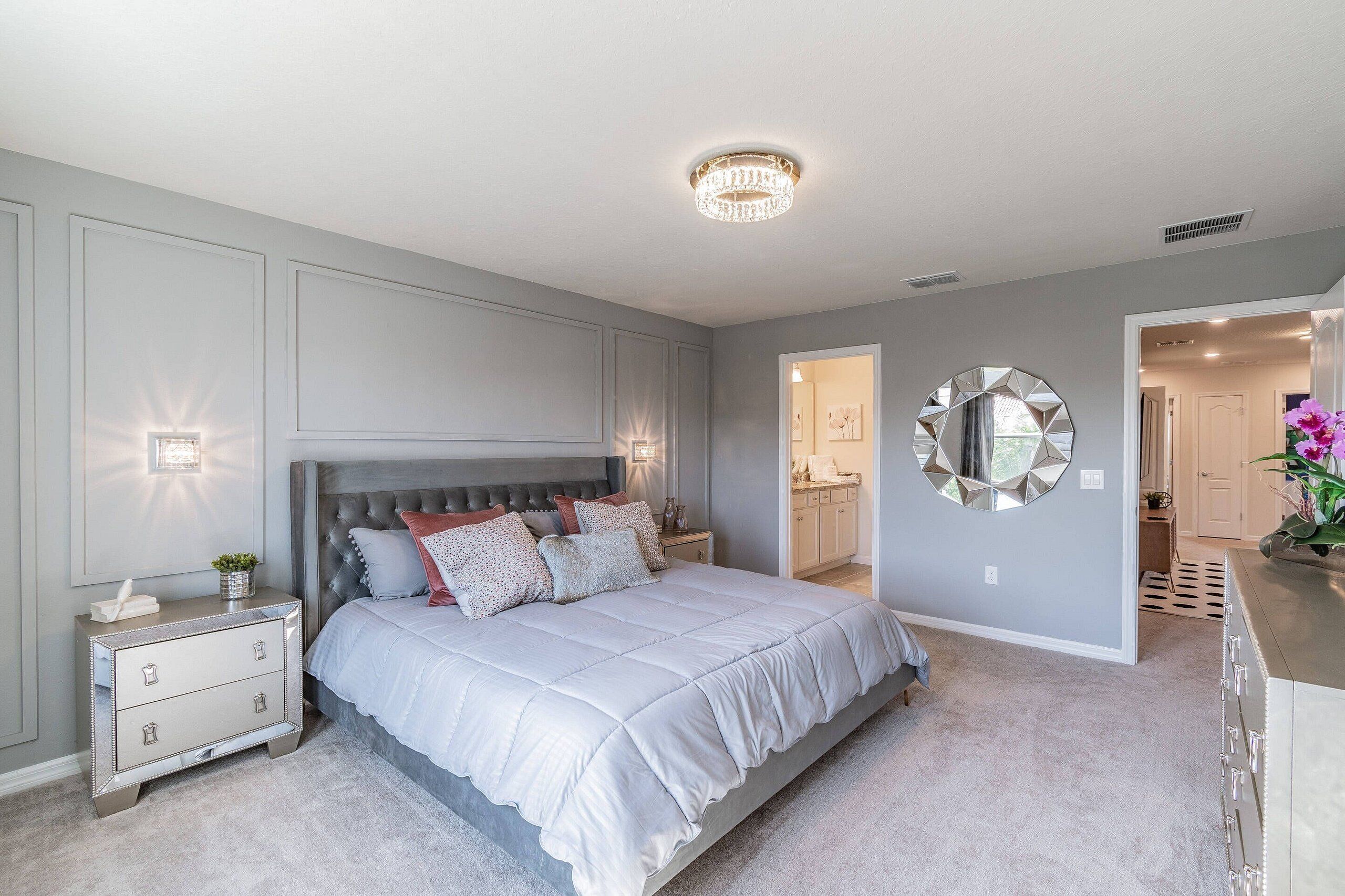 A bedroom with a large bed, bedside tables, a dresser, and a mirror on the wall.