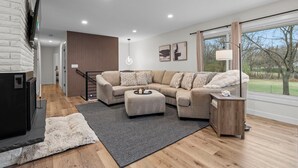 A modern living room with a sectional sofa, ottoman, and a fireplace.