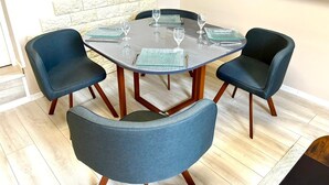 A dining area with a round table and four chairs, each with a blue cushion.
