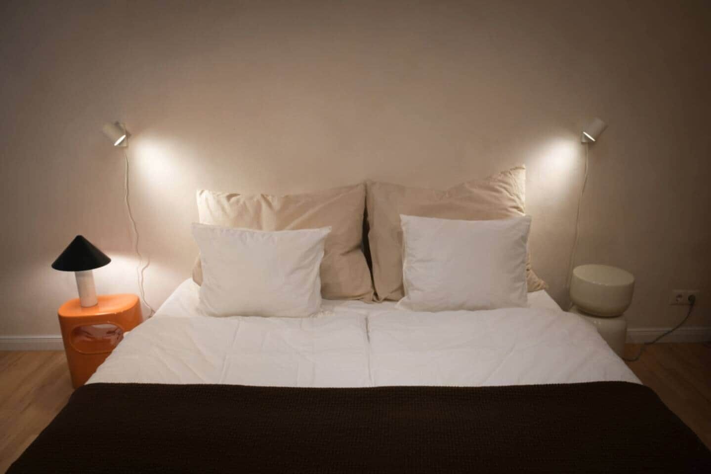 A neatly made bed with white bedding and two bedside lamps.
