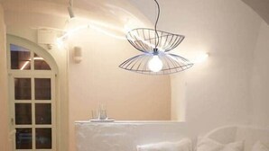 Un coin repas avec une table ronde, des chaises blanches et un luminaire suspendu au design moderne.