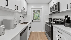 A modern kitchen with white cabinets, a microwave, a toaster, and a coffee maker. - The Tide: 2 Miles to Atlantic Ave - Walk to Beach (Delray Beach)