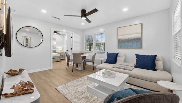 A modern living room with a sofa, coffee table, and dining area. - The Tide: 2 Miles to Atlantic Ave - Walk to Beach (Delray Beach)