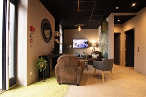 A modern living room with a sofa, armchairs, a TV, and a decorative mirror.