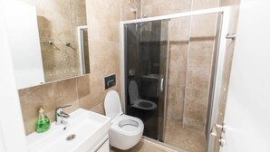 A modern bathroom with a glass-enclosed shower, a white sink, and a toilet.