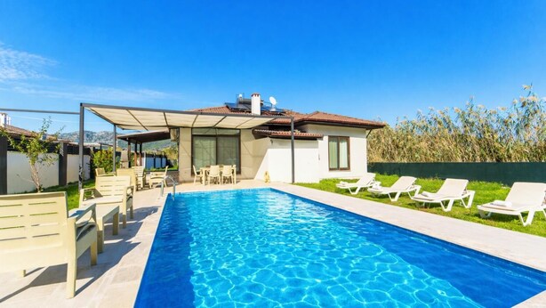 A modern house with a swimming pool, outdoor seating, and a view of the mountains.
