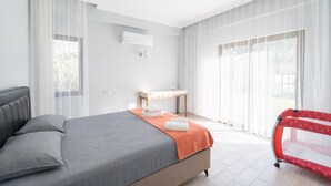 A bedroom with a bed, a bedside table, an air conditioning unit, and a window with curtains.