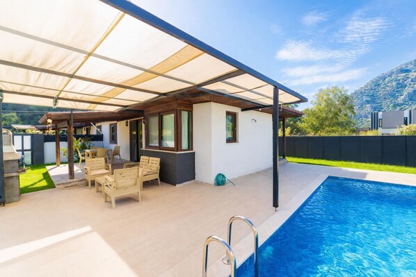 A covered outdoor area with a pool, wooden furniture, and a barbecue grill. - Villa Larisa - Two Bedroom Villa, Sleeps 4 (Mergenli)